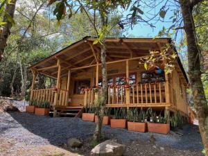 a wooden cabin with a porch in the woods at Cabaña en Villa de Leyva Se Permiten Mascotas Pet Friendly in Villa de Leyva