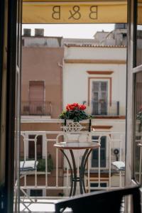 een tafel met een vaas met bloemen op een balkon bij B&B Palazzo Melluso in Porto Empedocle