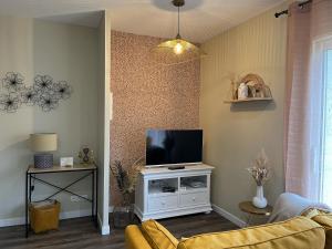 a living room with a tv on a white cabinet at Les Chenes Rouges in Veyrines-de-Domme