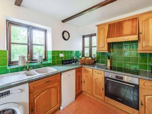 a kitchen with wooden cabinets and green tiles at 3 Bed in Bishops Tawton 75872 in Umberleigh Bridge