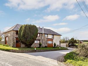 a stone house with a tree on the side of a road at 3 Bed in Umberleigh 65851 in Atherington