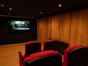 a conference room with red chairs and a television at Comfortable house with hot tub and cinema in nature in Hoenderloo