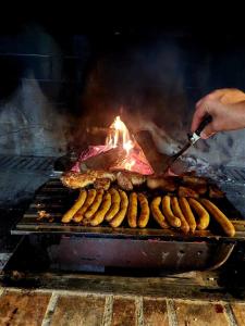 une personne qui prépare des saucisses et de la viande sur un grill dans l'établissement Apartman VikendicaManja Banja Luka, à Banja Luka