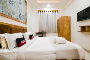 a bedroom with a large white bed with white pillows at Aceotel Inn Flamingo Vijay Nagar in Indore