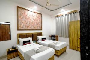 a bedroom with two beds and a painting on the wall at Aceotel Inn Flamingo Vijay Nagar in Indore