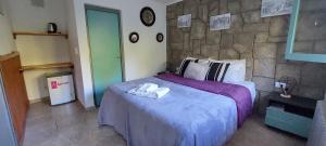 a bedroom with a large bed with a stone wall at Hosteria El Ceibo in La Cumbrecita