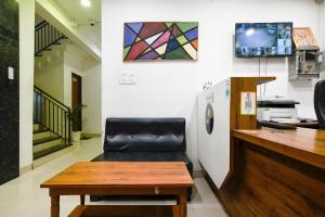 a room with a bench and a table and a refrigerator at Aceotel Inn Flamingo in Indore