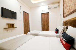 a hotel room with two beds and a tv at Aceotel Inn Flamingo Vijay Nagar in Indore
