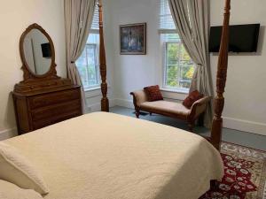 una camera con letto, specchio e sedia di Madison Manor II by the River Hot Tub Downtown a Madison