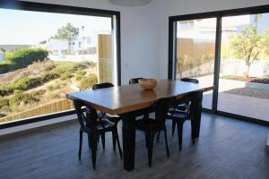 a dining room table with black chairs and a large window at H36 Pine Villa in Aljezur