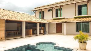a villa with a swimming pool in front of a house at NossoApê Guarua: Piscina | Churrasqueira | Ar-condicionado in Juiz de Fora