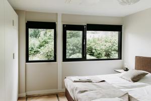 a bedroom with two beds and two windows at Forest Bungalow 1 - Hottub - Nature - Relax in Rheezerveen