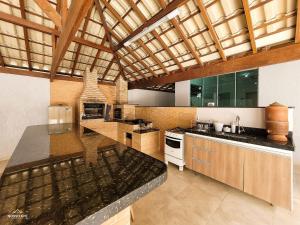 uma grande cozinha com armários de madeira e uma bancada em NossoApê Guarua: Piscina | Churrasqueira | Ar-condicionado em Juiz de Fora