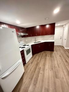 a kitchen with white appliances and wooden cabinets at Treasure’s Beautiful Basement in Brampton