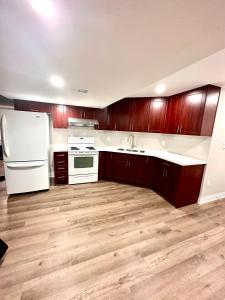 a kitchen with wooden cabinets and a white refrigerator at Treasure’s Beautiful Basement in Brampton