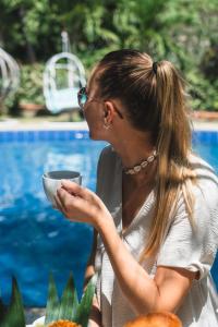 Una donna seduta accanto a una piscina con una ciotola in mano di Sundaras Resort & Spa Dambulla a Dambulla