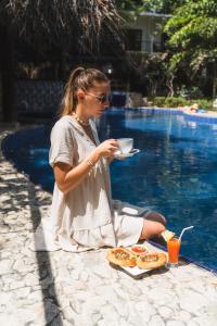 a woman sitting next to a pool with a plate of food at Sundaras Resort & Spa Dambulla in Dambulla