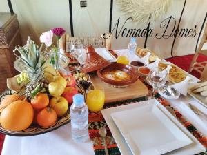 a table topped with a plate of fruit and juice at Nomada Domes in Merzouga