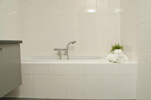 een witte badkamer met een bad met een kraan bij Hotel Apartments Belgium I in Geel