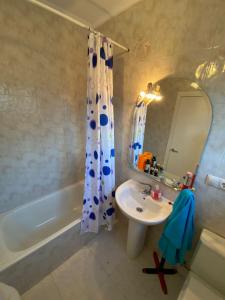 een badkamer met een wastafel, een bad en een douchegordijn bij LA CASINA DE VEGA in Gijón