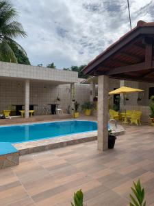 a swimming pool with a patio with tables and chairs at Casa Porto in Porto De Galinhas