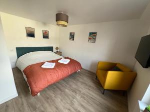 una camera da letto con un letto e una sedia gialla di Proche château - Calme, Confortable, Tout équipé a Fougères Altre 3 foto
