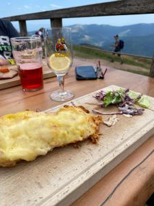 un trozo de pizza en una tabla de cortar con una copa de vino en LE VERTBRUCHE - Gîte avec superbe vue pour 15 pers, en La Bresse
