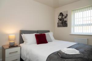 a bedroom with a large white bed with a red pillow at Spacious New Build - Free Parking & TV in each Bedroom in Macclesfield