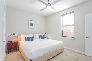 - une chambre blanche avec un lit et un ventilateur de plafond dans l'établissement TWO CozySuites Classy Music Row Condos w parking, à Nashville