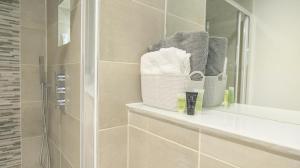 a bathroom with a shower with towels and a mirror at City Centre Seaview Apartment in Brighton & Hove