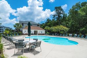 a pool with chairs and a table and a umbrella at Barefoot Resort - Arbor Trace 523 - Windy Hill in North Myrtle Beach