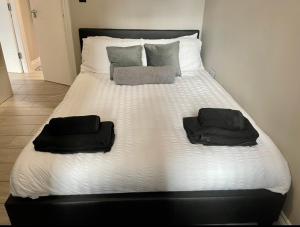 a white bed with two black towels on it at City Centre Seaview Apartment in Brighton & Hove