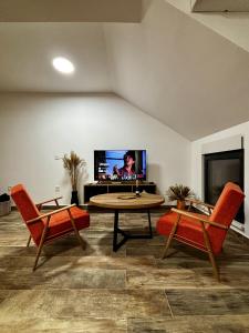 een woonkamer met 2 stoelen, een tafel en een tv bij Studio 19 A in Vrdnik