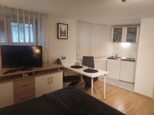 a room with a desk with a television and a kitchen at Bonitoapartamento-Vienna in Vienna