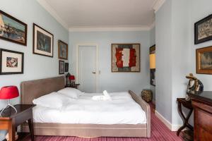 una camera da letto con un letto con lenzuola bianche e quadri alle pareti di Charming apartment in the heart of Paris - Welkeys a Parigi