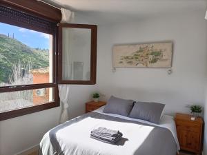 El Mirador del Valle FACIL ACCESO con COCHE في طليطلة: غرفة نوم بسرير ونافذة عليها مناشف