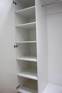 a closet with white shelves in a room at Small, quiet and central studio i Oslo in Oslo