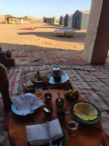 a table with plates of food on the beach at Camp Mbark authentic in Mhamid