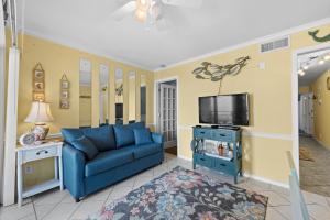 uma sala de estar com um sofá azul e uma televisão em A Place At The Beach WH 308 - Oceanfront - Windy Hill Section em Myrtle Beach