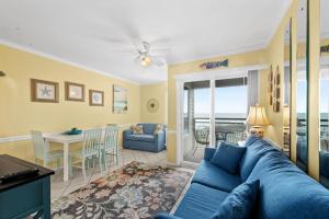 uma sala de estar com um sofá azul e uma sala de jantar em A Place At The Beach WH 308 - Oceanfront - Windy Hill Section em Myrtle Beach