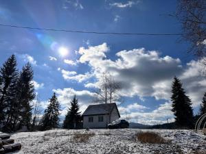 a small house on a snow covered hill with the sun at Zlatarski Pogled in Nova Varoš
