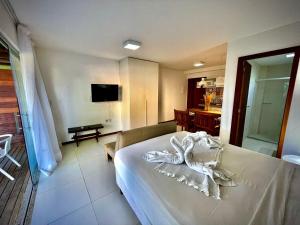 ein Hotelzimmer mit einem Bett und einem TV in der Unterkunft Bangalô Villas do pratagy com jacuzzi c in Maceió