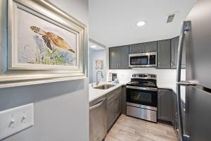 uma cozinha com um lavatório e um fogão forno superior em Ocean Creek Resort L4 -Oceanfront - Windy Hill em Myrtle Beach