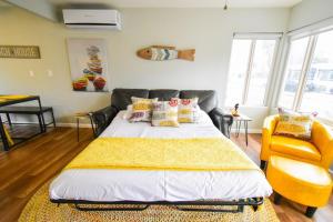 a bedroom with a bed and a yellow chair at Beach-2-Bay 1br - In the Heart of Mission Beach in San Diego