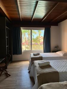 1 dormitorio con 2 camas y ventana grande en Pousada Vista da Barra, en Cassino