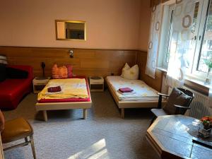 a room with two beds and a red couch at Hotel Bender in Eschweiler
