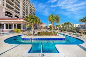 a swimming pool with palm trees and a building at Tilghman Beach & Golf Resort 6015 - 2nd Row - Cherry Grove in Myrtle Beach