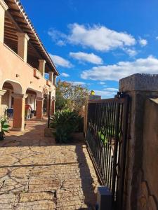 einen Zaun vor einem Haus mit einem Himmel in der Unterkunft Gelsi Holiday Home La Maddalena in La Maddalena
