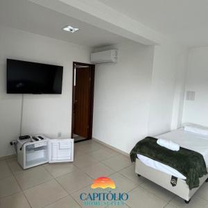 1 dormitorio con 1 cama y TV de pantalla plana en Capitólio Home Suítes en Capitólio