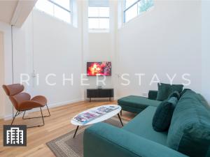 a living room with a blue couch and a table at Exquisite 3BR Duplex Period Conversion, Air-con & Amenities in London
